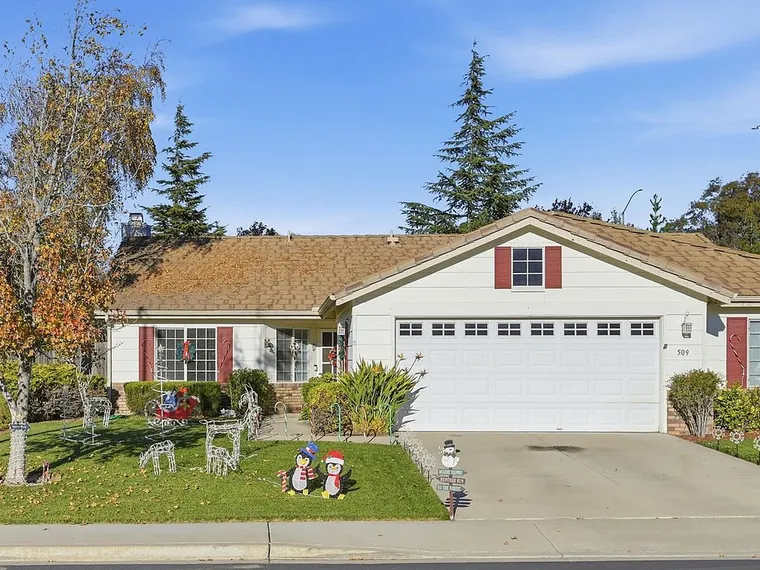 Single story white home with red shutters, a two car garage and a front lawn under tall pines at 509 Farmland Dr, Buellton, CA 93427